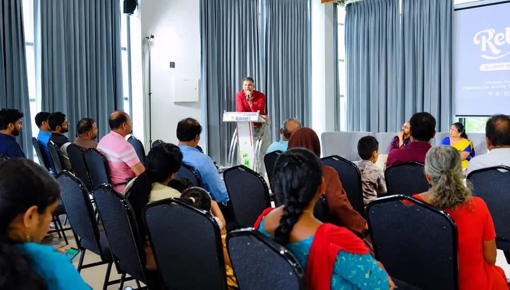 Members of the Al Shifa College of Nursing Alumni Association at an alumni meet, listening to a speaker at the podium